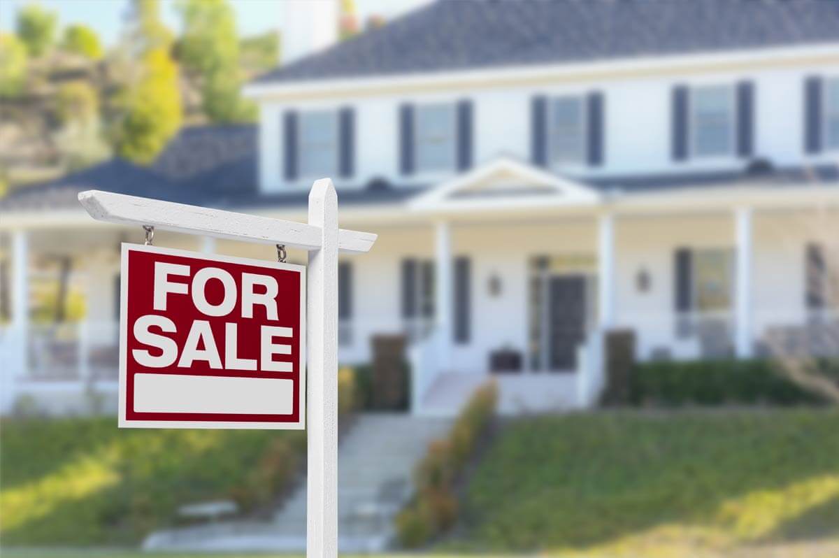 A suburban house with a for sale sign in front